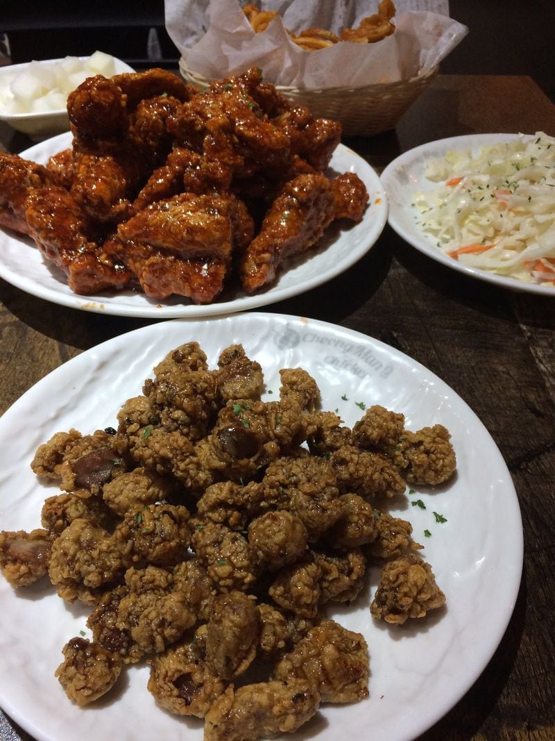 Chicken gizzards are prepared “tikku” style at Choong Man Chicken in Duluth, meaning they are fried, baked and drizzled with sauce. Behind them are a whole fried chicken with “garlic spicy” sauce, an order of curly fries and coleslaw. CONTRIBUTED BY WENDELL BROCK