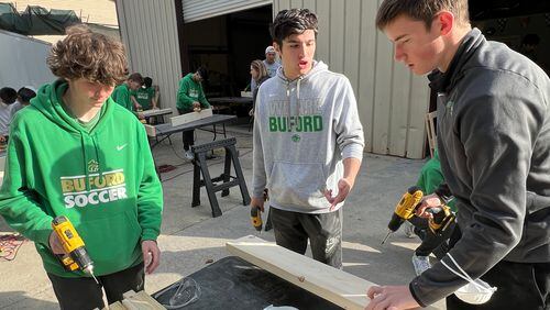 Buford High seniors and varsity soccer players Ashton Rubin (left), Marco Borrego (center) and Nathan Montini (right) assemble bed side rails during a Sleep in Heavenly Peace volunteer bed build in March.