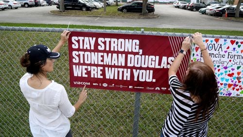 Volunteers hang banners around the perimeter of Marjory Stoneman Douglas High School to welcome back students who will be returning to school Wednesday, Feb. 28, 2018, two weeks after the mass shooting that killed 17 students and staff. (Susan Stocker/Sun Sentinel/TNS)