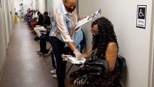 Xavier Benjamin fills out paperwork before voting at the South Fulton Service Center early on Friday morning, May 22, 20220. Benjamin said she arrived at the center at 6:20 am to secure her first place in line. STEVE SCHAEFER FOR THE ATLANTA JOURNAL-CONSTITUTION