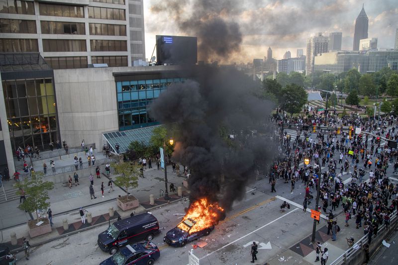 05/29/2020 - Atlanta, Georgia - An Atlanta Police Department patrol car is engulfed in flames after demonstrators set it ablaze and destroyed other patrol cars outside of the CNN Center in Atlanta, Friday, May 29, 2020. Following a peaceful march to the Georgia State Capitol to protest racial injustice and police brutality, demonstrators returned to the area around Centennial Olympic Park and CNN center and clashed with police. (ALYSSA POINTER / ALYSSA.POINTER@AJC.COM)