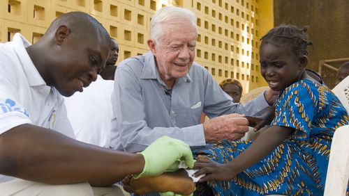Jimmy Carter consoles a young patient having a Guinea worm removed from her body in Savelugu, Ghana, in February 2007. The Carter Center lead the international campaign to eradicate Guinea worm disease. (The Carter Center)