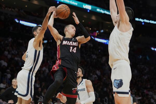 Memphis Grizzlies forward Santi Aldama (7) and center Zach Edey (14) defend Miami Heat guard Tyler Herro (14) during the first half of an NBA basketball game, Thursday, April 3, 2025, in Miami. (AP Photo/Marta Lavandier)