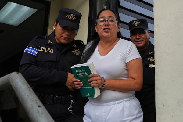 Human rights lawyer Ruth Eleonora Lopez, handcuffed, holds a bible as police escort her out of her court hearing in San Salvador, El Salvador, Wednesday, June 4, 2025. (AP Photo/Salvador Melendez)