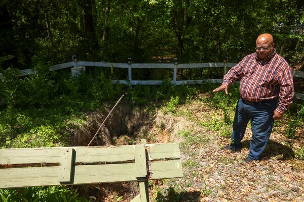 Tony Dunbar discusses the sink hole in the common area at Willow Brook in Roswell. Also shown is a picnic table that was destroyed by the sink hole. Jason Getz / Jason.Getz@ajc.com)
