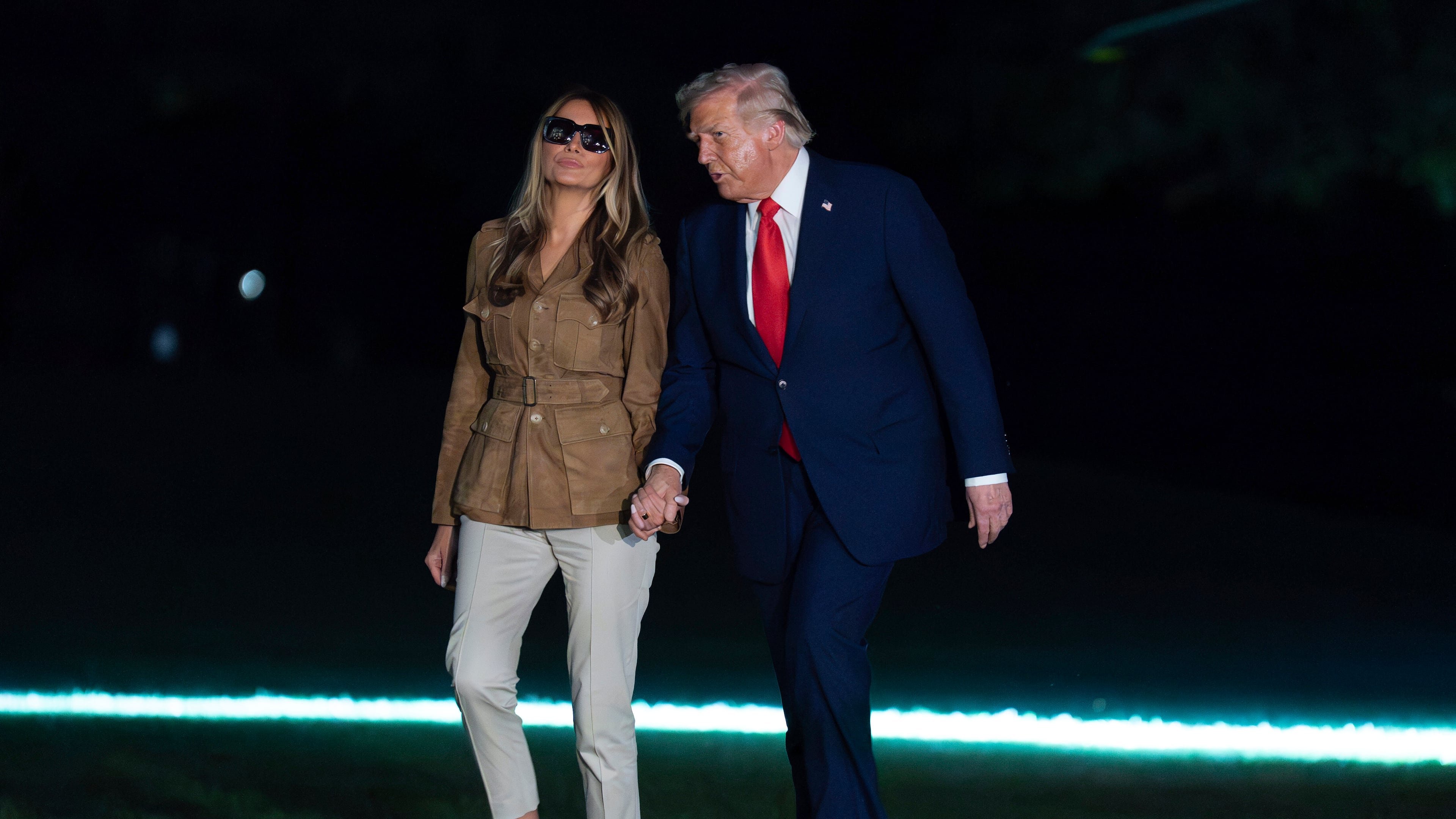 President Donald Trump holds hands with first lady Melania Trump as they walk on the South Lawn upon their arrival to the White House, in Washington, Thursday, Sept. 18, 2025. (AP Photo/Jose Luis Magana)
