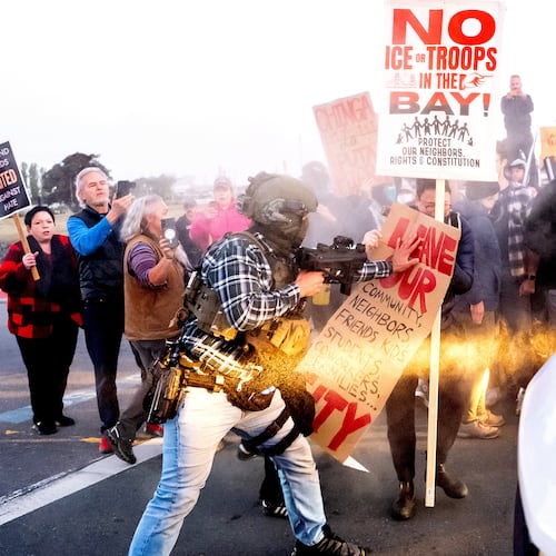 A person pushes a protester blocking a caravan of U.S. Customs and Border Protection personnel trying to enter Coast Guard Base Alameda on Thursday, Oct. 23, 2025, in Oakland, Calif. (AP Photo/Noah Berger)