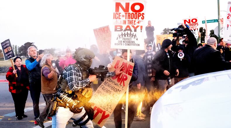A person pushes a protester blocking a caravan of U.S. Customs and Border Protection personnel trying to enter Coast Guard Base Alameda on Thursday, Oct. 23, 2025, in Oakland, Calif. (AP Photo/Noah Berger)