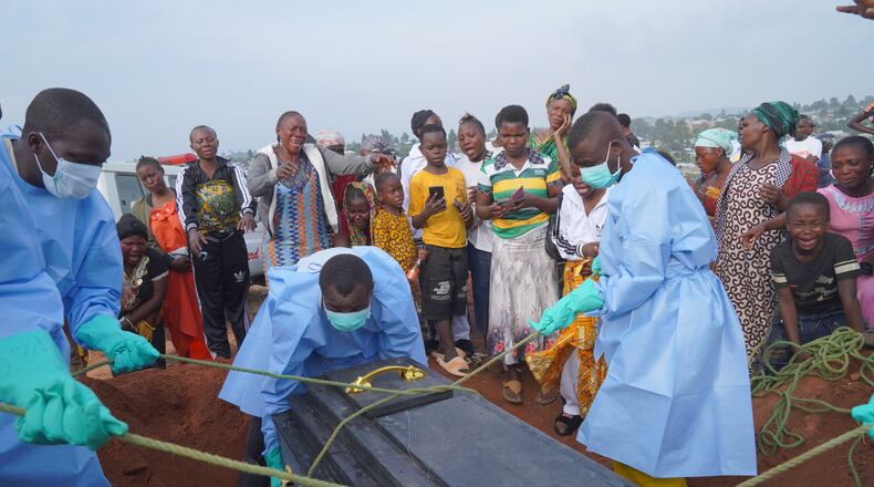 People dressed in protective gear lower into a grave the coffin containing the remains of Jeannine Katusabe, who died of Ebola, during a burial service in Bunia, Ituri province, eastern Congo, Tuesday, Aug. 11, 2026. (AP Photo/Dieudonne Dirole)