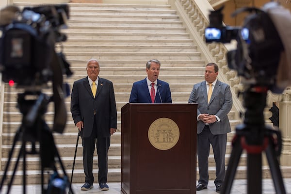 Georgia Public Service Commissioner Lauren “Bubba” McDonald (from left), Gov. Brian Kemp and PSC chairman Jason Shaw announce Georgia Power has reached a deal with the PSC to keep its current base electricity rates in place for the next three years. (Arvin Temkar/AJC)