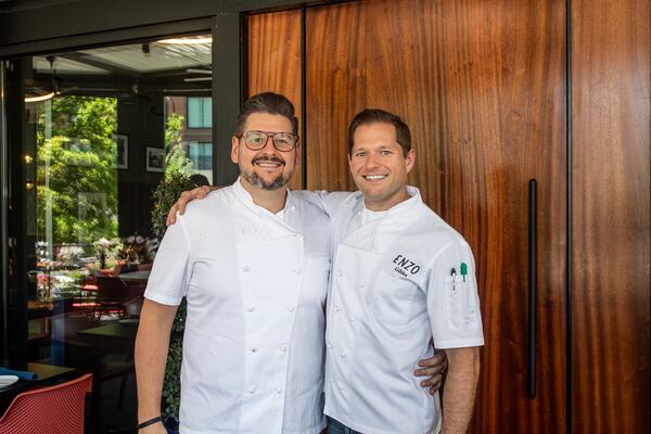Chef Andrea Montobbio stands smiling with his arm around chef de cuisine David Gibbs, who is also smiling at the camera. Both wear white chef coats.