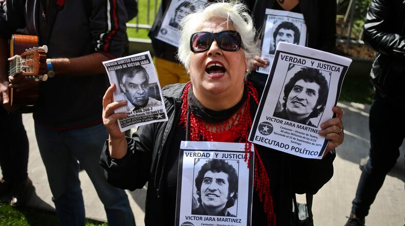 FILE -Members of the Funa Commission shout slogans outside the home of Edwin Dimter Bianchi, accused and on trial for the murder of Chilean singer-songwriter Victor Jara, during a demonstration to publicly shame him in Santiago, Chile, April 22, 2017. (AP Photo/Esteban Felix, File)