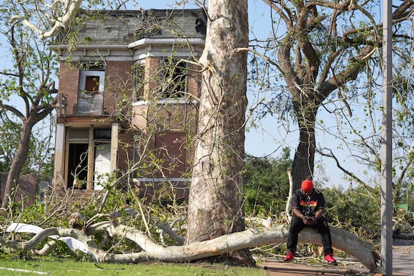 Steven Lampink sits on a downed tree after a severe storm moved through Friday, May 16, 2025, in St. Louis. (AP Photo/Jeff Roberson)
