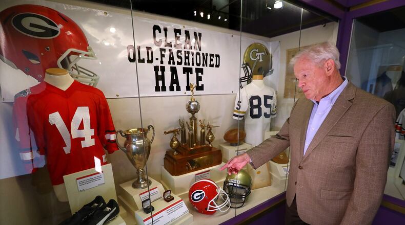 Jim McLendon, the executive director of the Georgia Sports Hall of Fame, discusses some of the items in one of the Georgia and Georgia Tech football displays. Curtis Compton/ccompton@ajc.com