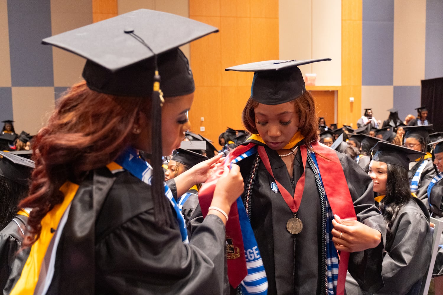 Jamecia Phillips, left, helps arrange Zahrria Thomas’ gown and sashes before the start of the Spelman College graduation ceremony at the Georgia International Convention Center in College Park on Sunday, May 18, 2025.   Ben Gray for the Atlanta Journal-Constitution