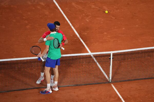 Winner Italy's Jannik Sinner, back to the camera, and Serbia's Novak Djokovic hug after their semifinal match of the French Tennis Open at the Roland-Garros stadium in Paris, Friday, June 6, 2025. (AP Photo/Lindsey Wasson)