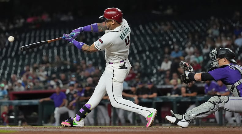 Arizona Diamondbacks' Ketel Marte (4) hits a run-scoring single as Colorado Rockies catcher Brett Sullivan reaches for the ball during the first inning of a baseball game, Wednesday, Aug. 12, 2026, in Phoenix. (AP Photo/Ross D. Franklin)