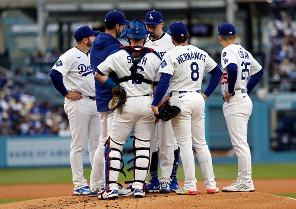 Los Angeles Dodgers' Blake Snell, center, gets a visit from pitching coach Josh Bard, left, and infielders during the second inning of a baseball game against the Atlanta Braves Wednesday, April 2, 2025, in Los Angeles. (AP Photo/Kevork Djansezian)