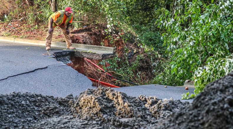 A worker surveys damage from a road that was washed away in Marietta after heavy rains fell Sept. 8. Cobb County commissioner Jerica Richardson will be hosting a community meeting at 5:30 p.m. Thursday to hear input from residents affected by the storm. (AJC File)