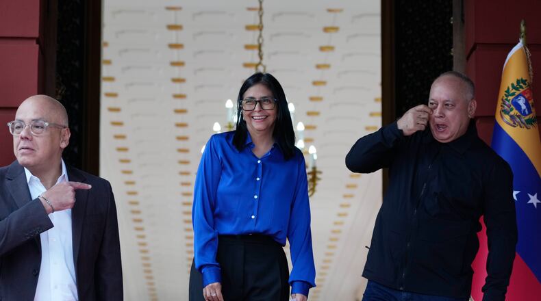 Venezuela's acting President Delcy Rodriguez, center, smiles flanked by Interior Minister Diosdado Cabello, right, and National Assembly President, her brother, Jorge Rodriguez, as they prepare ot make a statement in Caracas, Venezuela, Wednesday, Jan. 14, 2026. (AP Photo/Ariana Cubillos)