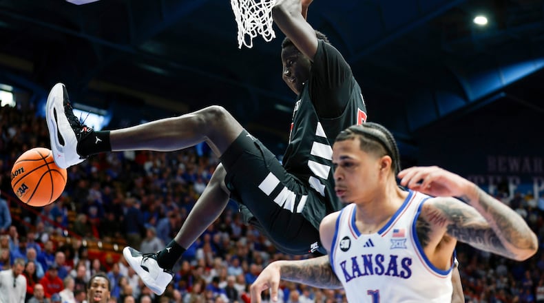 Cincinnati center Moustapha Thiam, top, dunks over Kansas guard Jayden Dawson (1) during the second half of an NCAA college basketball game, Saturday, Feb. 21, 2026, in Lawrence, Kan. (AP Photo/Colin E. Braley)