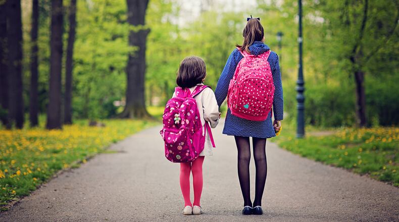 Two girls walk with bookbags