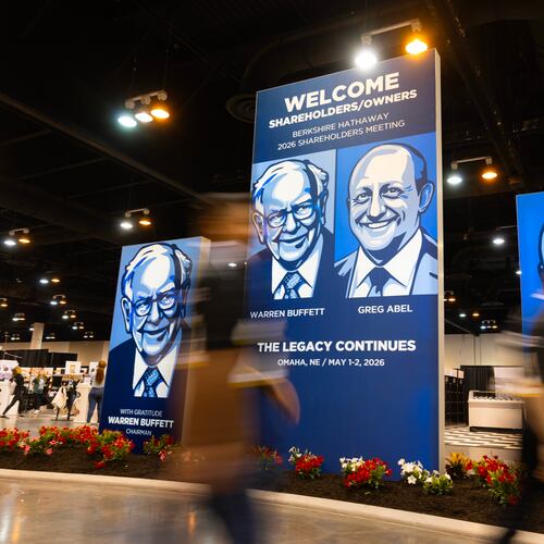 People walk past large portraits of Berkshire Hathaway's Warren Buffett, left, and CEO Greg Abel inside the Berkshire Hathaway annual meeting on Saturday, May 2, 2026, in Omaha, Neb. (AP Photo/Rebecca S. Gratz)