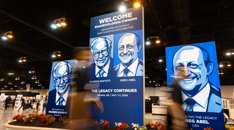 People walk past large portraits of Berkshire Hathaway's Warren Buffett, left, and CEO Greg Abel inside the Berkshire Hathaway annual meeting on Saturday, May 2, 2026, in Omaha, Neb. (AP Photo/Rebecca S. Gratz)