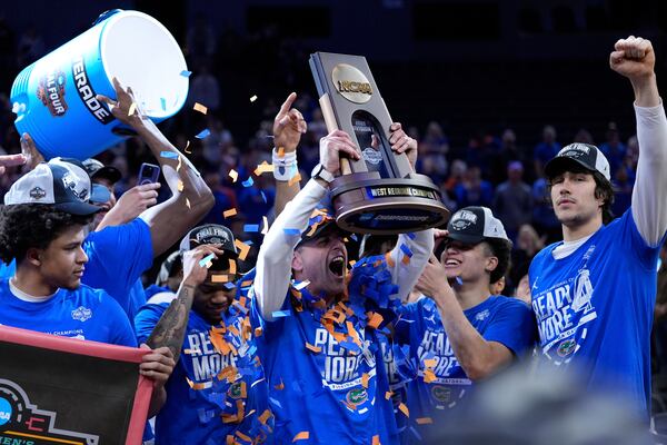 Florida head coach Todd Golden holds the trophy as he celebrates with his player after defeating Texas Tech in the Elite Eight of the NCAA college basketball tournament, Saturday, March 29, 2025, in San Francisco. (AP Photo/Godofredo A. Vásquez)