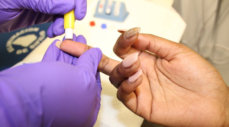 An unidentified woman gets her finger pricked for a HIV test recently in Atlanta. Contributed