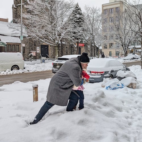 A man carries his daughter over a snowbank outside a day care center in the Brooklyn borough of New York, on Wednesday, Feb. 25, 2026. (AP Photo/Drew Callister)