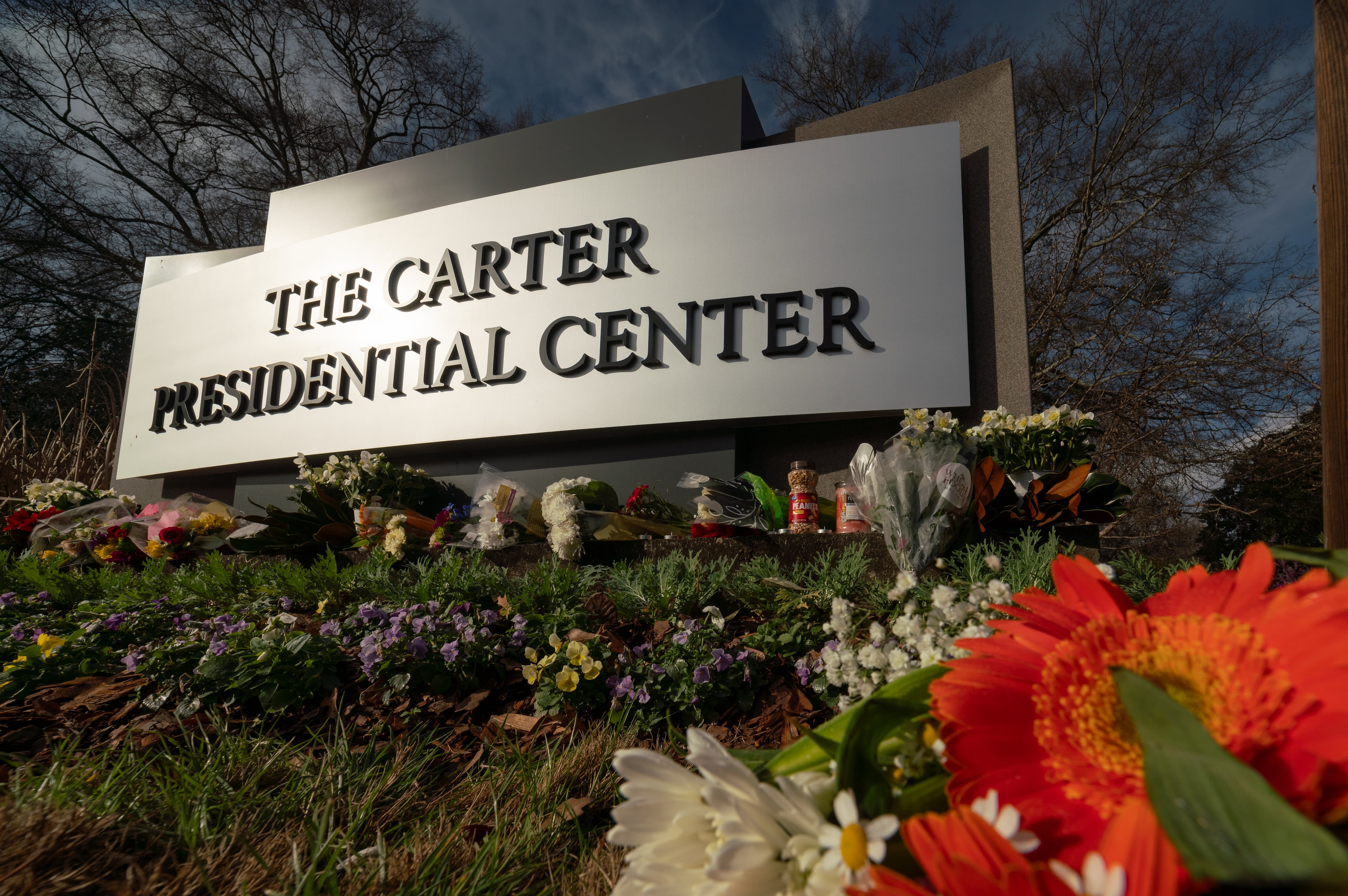 Flowers, candles and peanuts line the sign at The Carter Presidential Center in Atlanta,Georgia after the death of the former president.