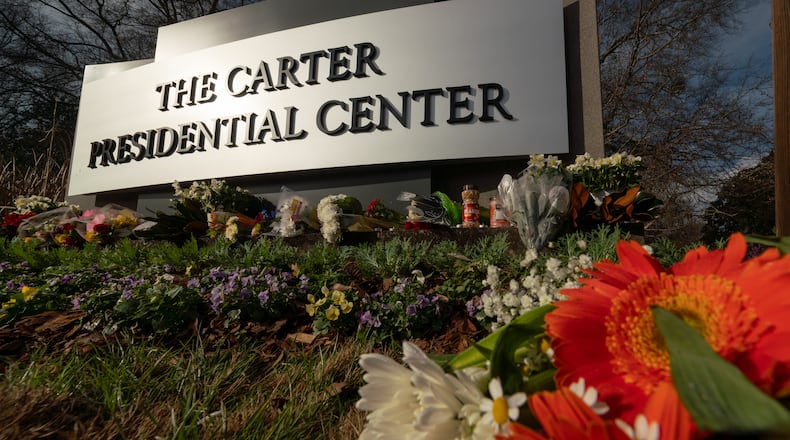 Flowers adorn the sign in front of the Carter Presidential Center in Atlanta on Dec. 30. (Ben Hendren for the Atlanta Journal-Constitution)