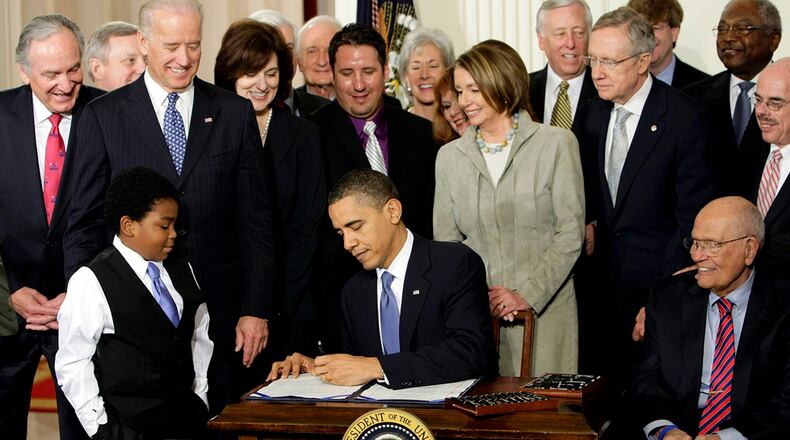 FILE - In this March 23, 2010 file photo, President Barack Obama signs the Affordable Care Act in the East Room of the White House in Washington. If Obama's health care law survives Supreme Court scrutiny, it will be nearly a decade before all its major pieces are in place. The law's carefully orchestrated phase-in is evidence of what's at stake in the Supreme Court deliberations that start March 26, 2012. With Obama are Marcelas Owens of Seattle, left, and Rep. John Dingell, D-Mich., right; from top left are Sen. Tom Harkin, D-Iowa., Senate Majority Whip Richard Durbin of Ill., Vice President Joe Biden, Vicki Kennedy, widow of Sen. Ted Kennedy, Sen. Christopher Dodd, D-Conn., Rep. Sander Levin, D-Mich., Ryan Smith of Turlock, Calif., Health and Human Services Secretary Kathleen Sebelius, House Speaker Nancy Pelosi of Calif., House Majority Leader Steny Hoyer of Md., Senate Majority Leader Harry Reid of Nev., Rep. Patrick Kennedy, D-R.I., House Majority Whip James Clyburn of S.C., and Rep. Henry Waxman, D-Calif. (AP Photo/J. Scott Applewhite, File)