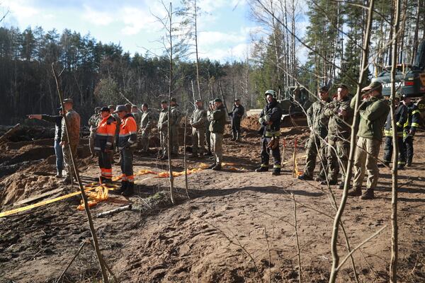 In this image provided by the U.S. Army, U.S. Army soldiers from the 1st Armored Brigade Combat Team, 3rd Infantry Division, along with Lithuanian Army and emergency services personnel, discuss their plan to recover four U.S. soldiers in a U.S. Army M88 Hercules submerged under several meters of water in a swamp near a training area near Pabadre, Lithuania, Thursday, March 27, 2025. (Trevor Wilson/U.S. Army via AP)