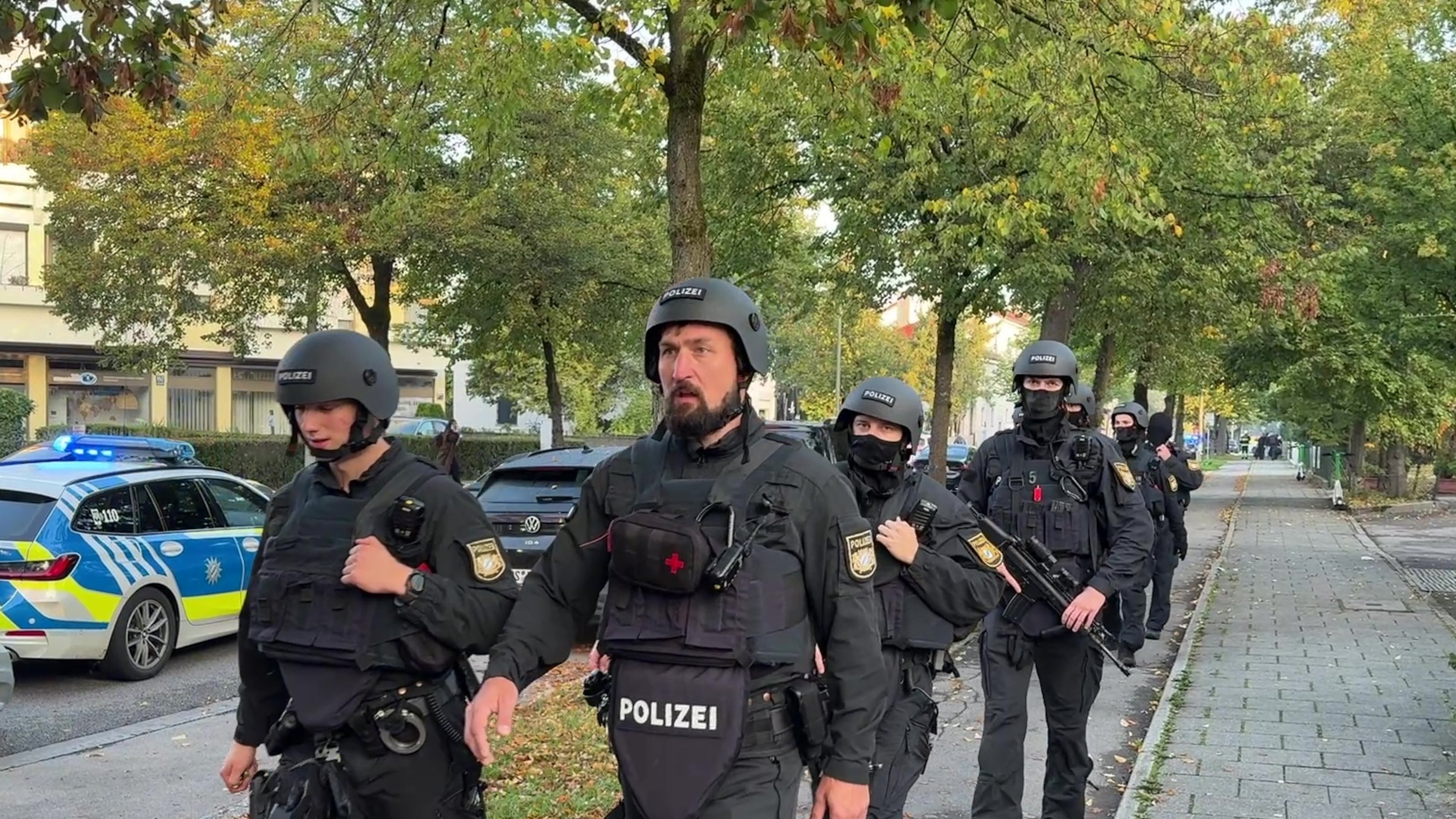 Police officers walk along a footpath after a fire in a detached house in Munich, Germany, Wednesday, Oct. 1, 2025. (Roland Freund/dpa via AP)