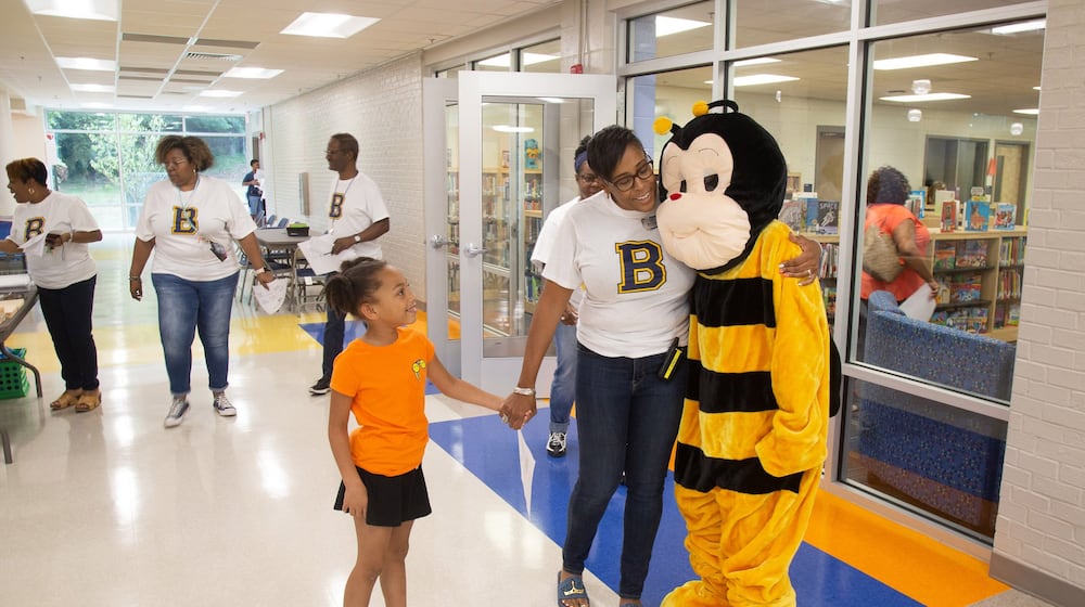 Beecher Hills Elementary school principal Crystal Jones (C) hugs the schools’ mascot while holding the hand of Olivia Sorel during the first open house after the schools’ extensive renovation Friday, August 9, 2019. STEVE SCHAEFER / SPECIAL TO THE AJC