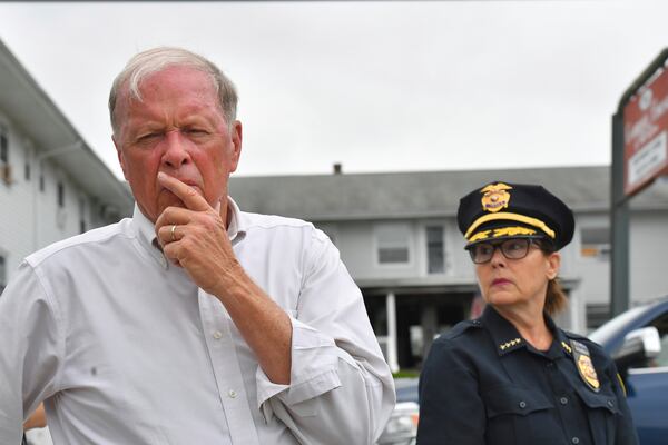 Fall River Mayor Paul Coogan, left, faces reporters near the Gabriel House assisted living facility, behind, Monday, July 14, 2025, following a fire at the facility that started late Sunday, in Fall River, Mass. (AP Photo/Steven Senne)