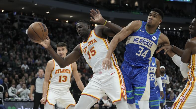 Giannis Antetokounmpo of the Bucks battles Hawks centers Clint Capela (left) and Onyeka Okongwu (right) for a loose ball during the second half of an NBA basketball game Saturday, Dec. 2, 2023, in Milwaukee. The Bucks won 132-121. (AP Photo/Morry Gash)