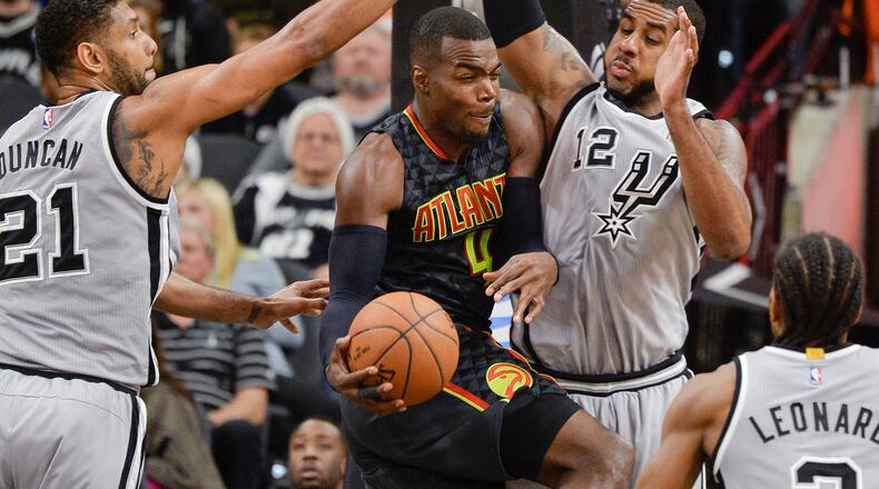 Atlanta Hawks forward Paul Millsap (4) looks to pass as he is defended by San Antonio Spurs’ LaMarcus Aldridge (12), Tim Duncan (21) and Kawhi Leonard during the first half of an NBA basketball game, Saturday, Nov. 28, 2015, in San Antonio. (AP Photo/Darren Abate)
