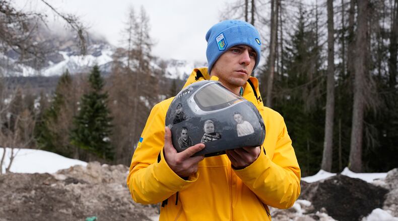 Ukrainian skeleton athlete Vladyslav Heraskevych holds his crash helmet as he stands outside the sliding center at the 2026 Winter Olympics, in Cortina d'Ampezzo, Italy, Thursday, Feb. 12, 2026. (AP Photo/Alessandra Tarantino)