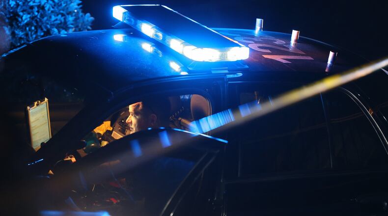 A DeKalb Police officer works from his car at the scene of an officer-involved shooting Monday where police responded to the wrong house on a burglary call. Ben Gray/bgray@ajc.com