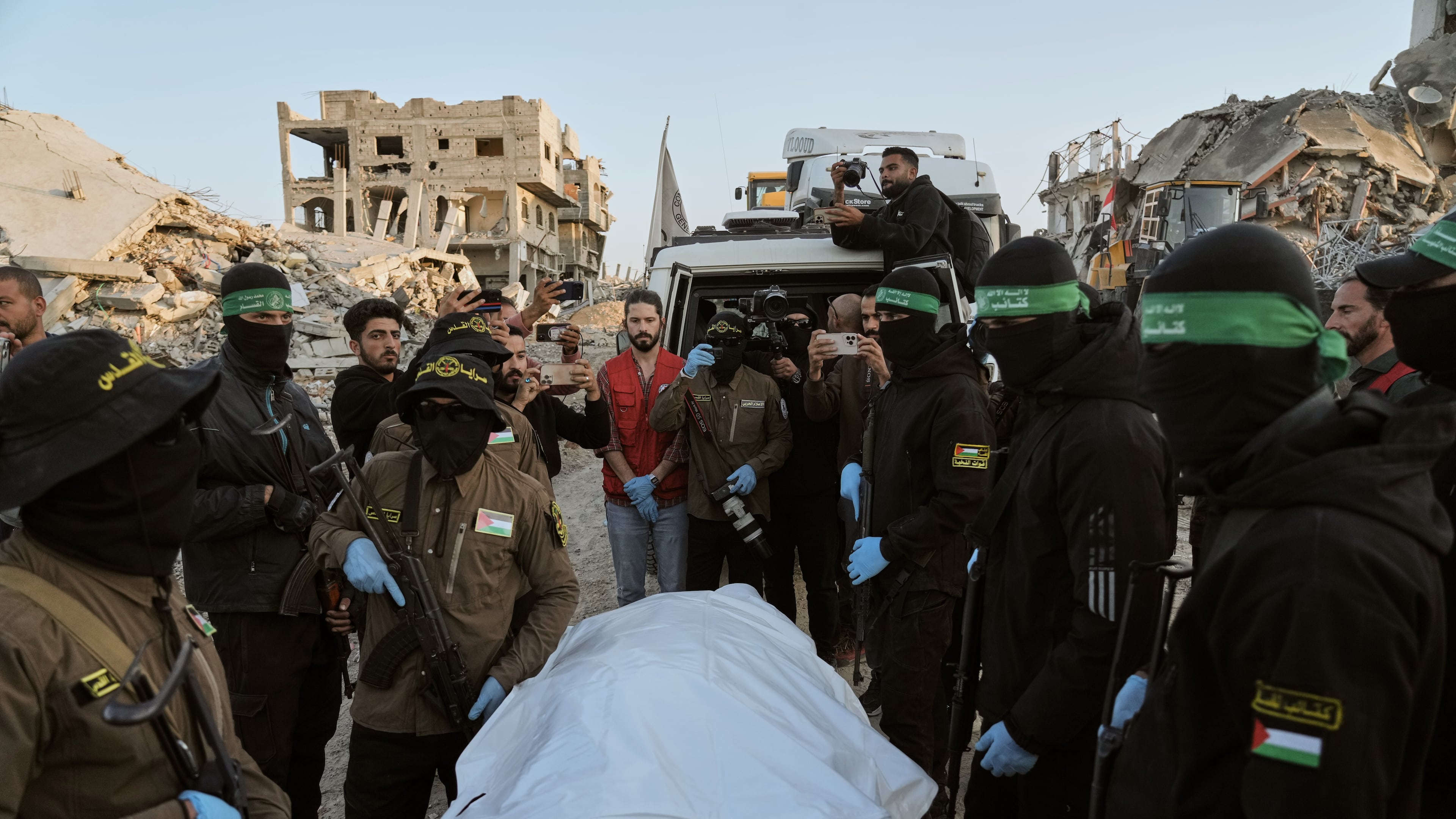 Masked Islamic Jihad and Hamas militants hand over a body bag believed to contain the remains of a deceased hostage to the Red Cross for transfer to Israeli authorities, in Beit Lahiya, in the northern Gaza Strip, Wednesday, Dec. 3, 2025. (AP Photo/Jehad Alshrafi)