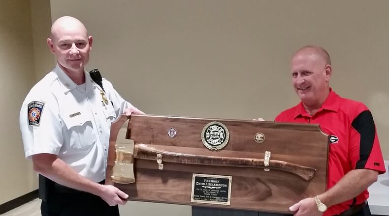 Interim Fayette County Fire Chief Jeff Hill presented retiring chief David Scarbrough with a commemorative axe noting Scarbrough's 34 years of service to the county. Courtesy Fayette County
