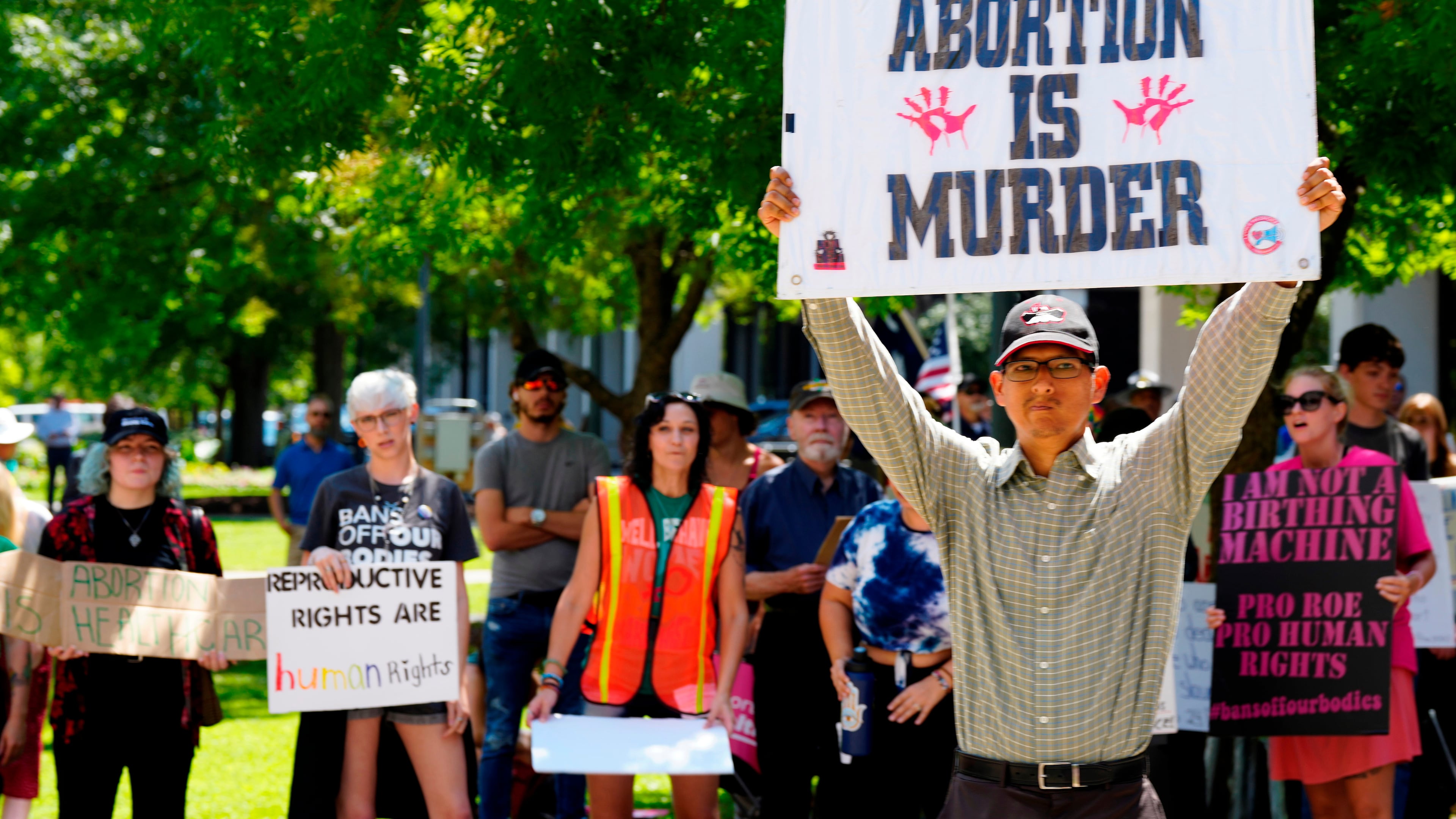 FILE - A man supporting restrictions on abortion holds a sign as abortion-rights supporters hold signs behind him outside the South Carolina Statehouse on Thursday, July 7, 2022, in Columbia, S.C. (AP Photo/Meg Kinnard, File)