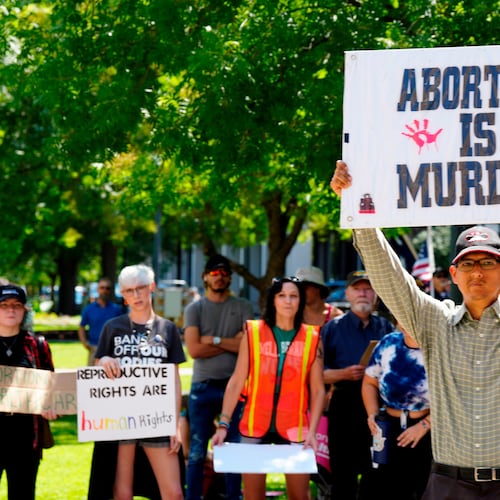 FILE - A man supporting restrictions on abortion holds a sign as abortion-rights supporters hold signs behind him outside the South Carolina Statehouse on Thursday, July 7, 2022, in Columbia, S.C. (AP Photo/Meg Kinnard, File)