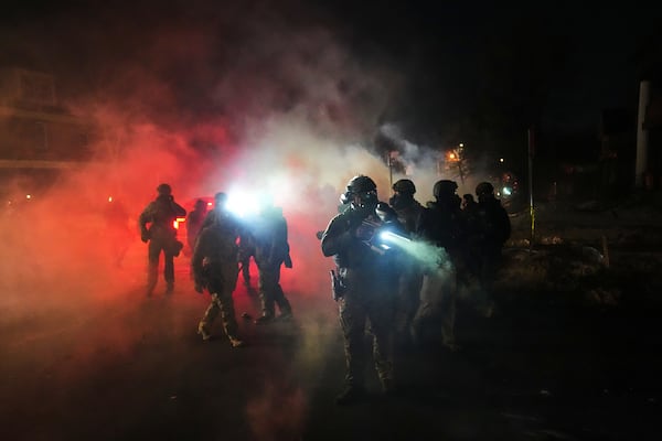 Law enforcement officers stand amid tear gas at the scene of a reported shooting on Wednesday, Jan. 14, 2026, in Minneapolis. “What happened in Minneapolis woke us up,” says Alex Vital, who owns a social club in Dalton. (Adam Gray/AP)