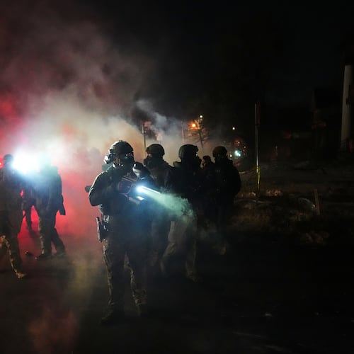 FILE - Law enforcement officers stand amid tear gas at the scene of a reported shooting, Jan. 14, 2026, in Minneapolis. (AP Photo/Adam Gray, File)