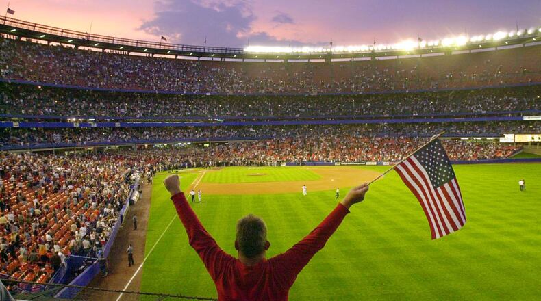 Bobby Amos stand with his arms in the air holding a flag before the start of a game between the New York Mets and the Atlanta Braves at Shea Stadium in New York Friday, Sept. 21, 2001. This was the first MLB game in New York after the World Trade Center attack of Sept. 11. Amos, of Queens, N.Y., lost his cousin, firefighter Tommy McCann, in the Trade Center disaster. (Mark Lennihan/AP)