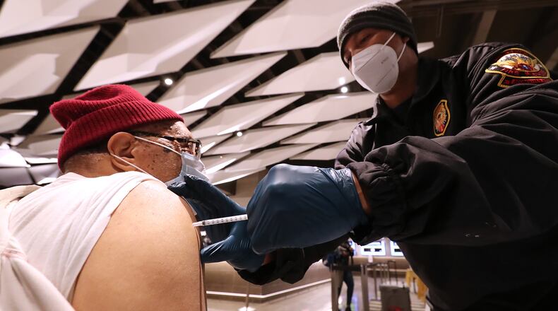 Philip McCollum gets a Pfizer vaccine from Atlanta Fire and Rescue Lt. Jathan Dortch at the Fulton County Board of Health mass vaccination program hosted at Mercedes-Benz Stadium on Wednesday, Jan. 13, 2021, in Atlanta. (Curtis Compton / Curtis.Compton@ajc.com)